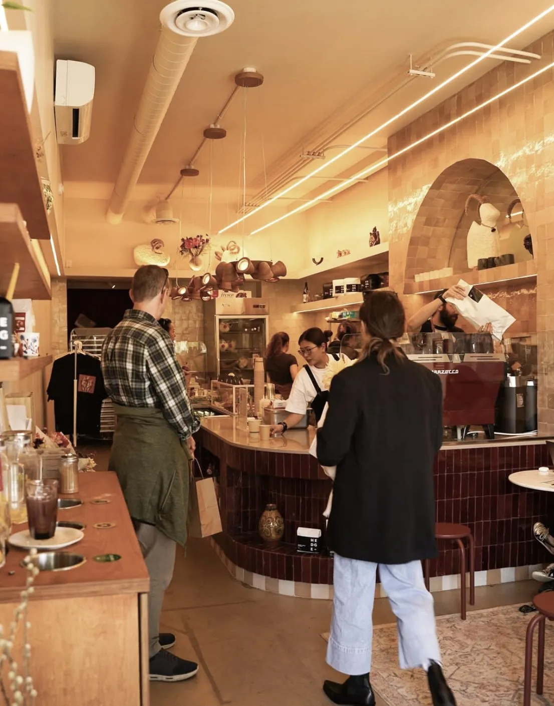 Guests ordering at the burgundy-tiled bar under linear lighting