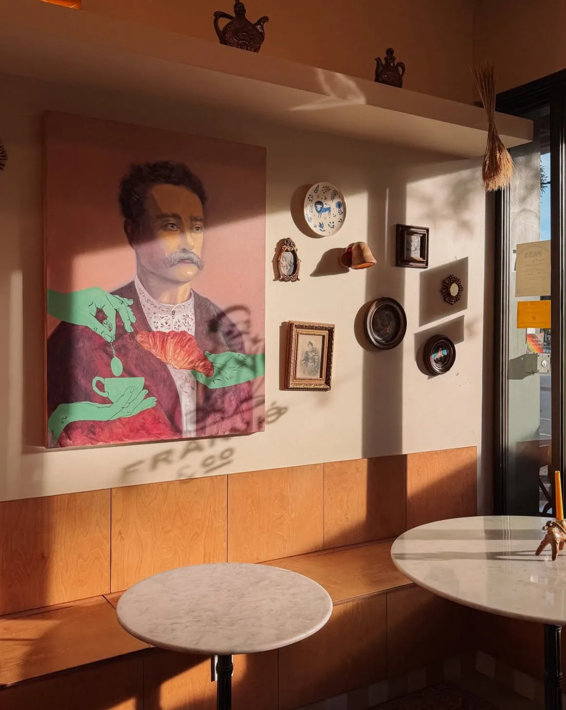 Portrait of Ivan Franko above the oak banquette, surrounded by collected plates and small framed pieces