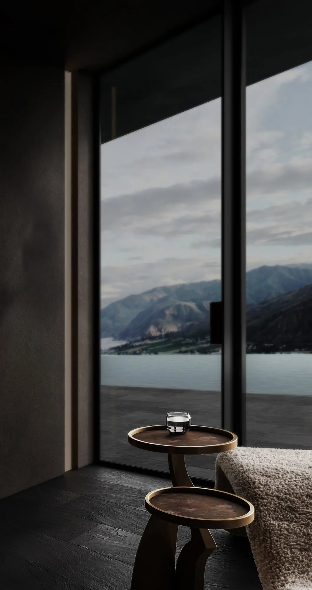 Corner window framing lake and mountain views above twin bronze pedestal tables and a bouclé lounger on slate flooring — Obsidian Oasis Spa